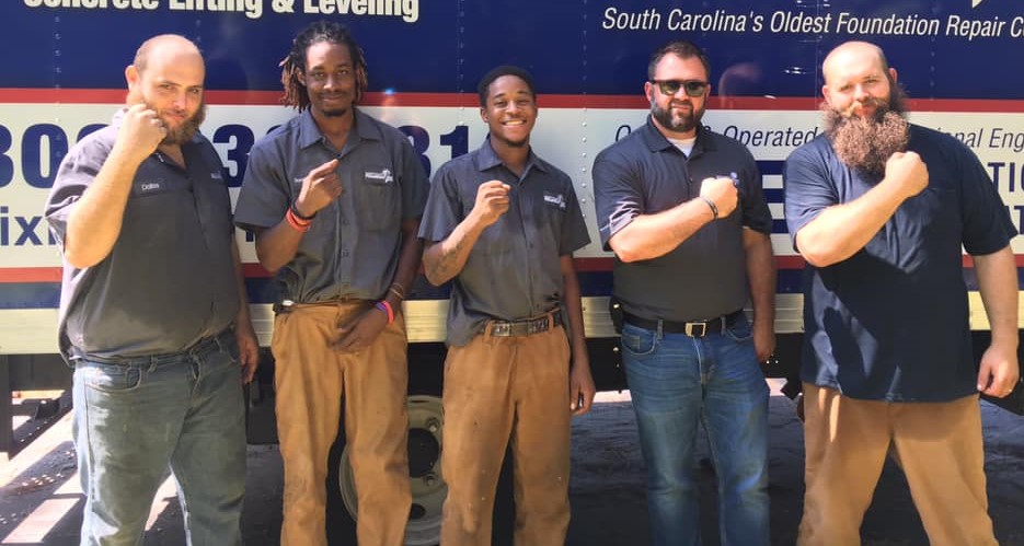 The crew outside smiling in front of the supply truck.